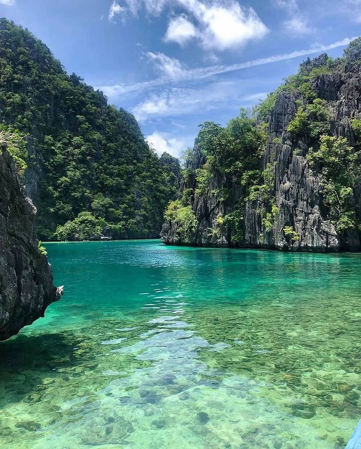 the water is crystal blue and clear with green trees on both sides, surrounded by mountains