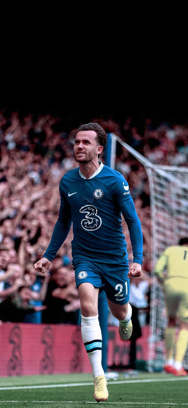 a soccer player is running on the field in front of an audience with his arms outstretched