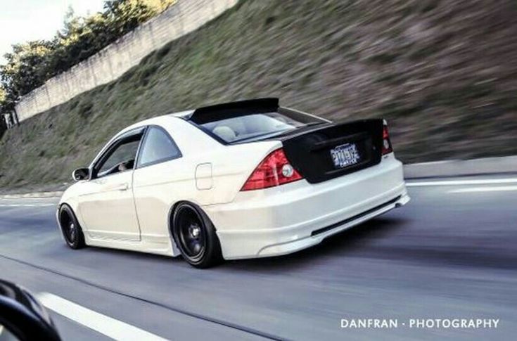 a white car driving down a road next to a hill