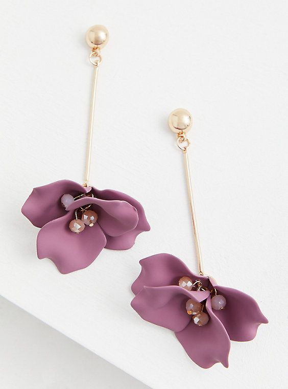 a pair of earrings with purple flowers and pearls on the ear wires, sitting on top of a white surface