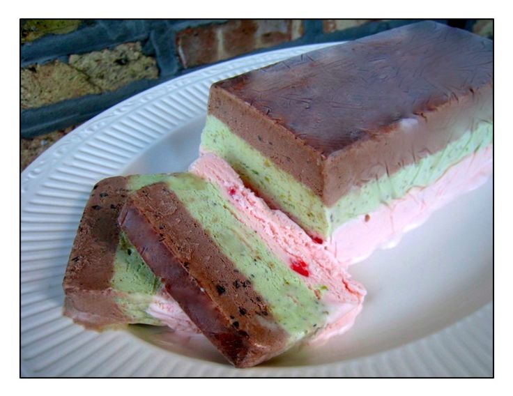 two pieces of cake sitting on top of a white plate with pink and green frosting