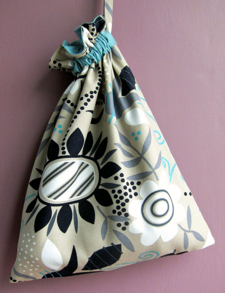 a bag hanging on the wall with a flower pattern and blue ribbon attached to it