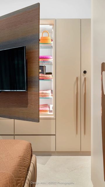 there is a television mounted on the wall in this modern bedroom with built - in shelving