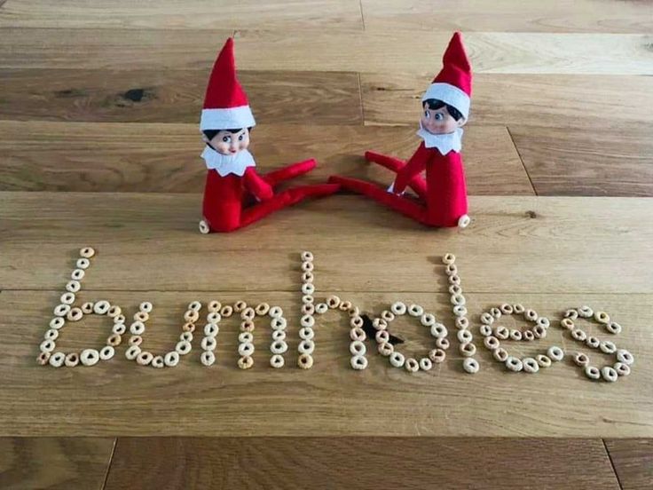 two elfs sitting on top of a wooden floor next to the word spelled out with letters