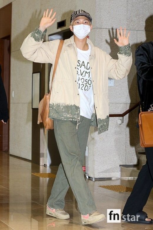 a person wearing a face mask and holding their hands up in the air while walking through an airport