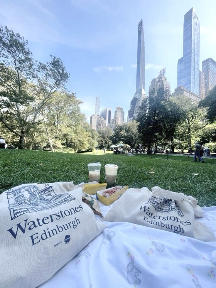 there is a picnic in the park with some drinks and food on the blanket outside