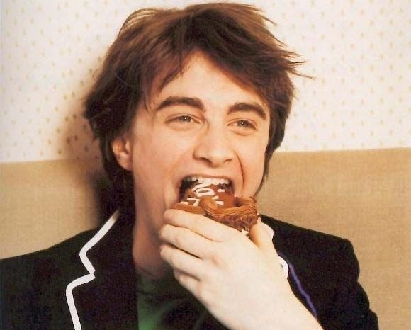 a man is eating a doughnut while sitting on a couch with his mouth open