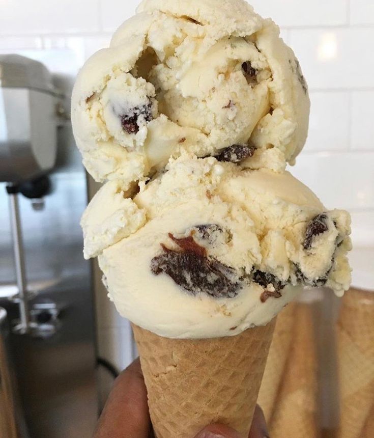 two scoops of ice cream in a cone with crumbled chocolate chunks on top