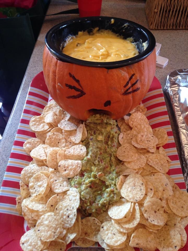 a cat face bowl with chips and dip in it on a plate next to an orange jack - o'- lantern