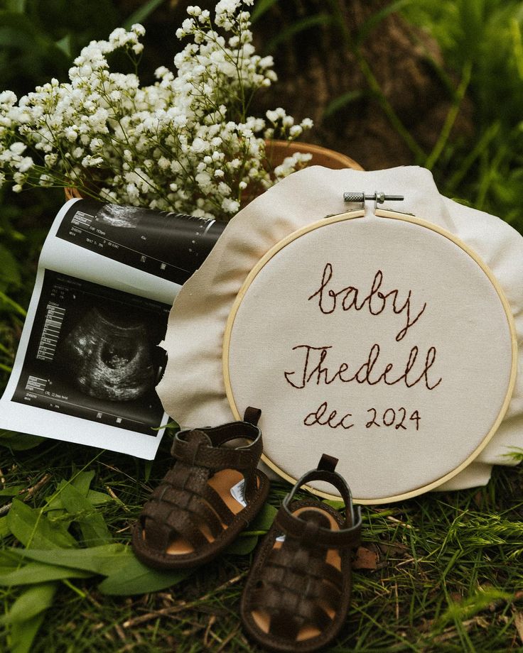 a baby's birth announcement with shoes and flowers on the ground next to it