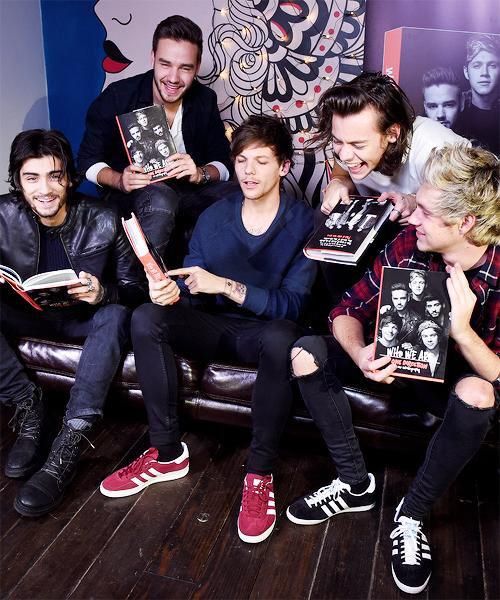 group of people sitting on couch with books in their hands