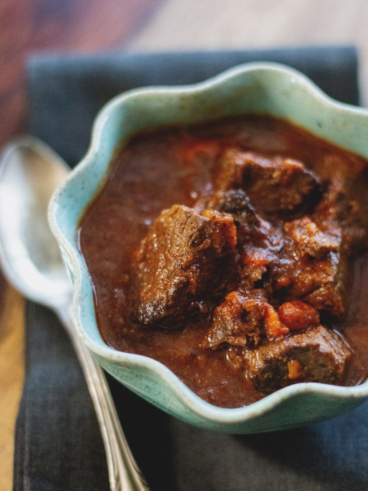 a bowl filled with beef chili next to a spoon