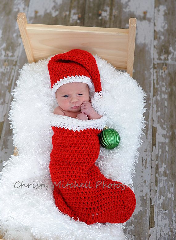 a baby wearing a santa hat and holding a green ornament