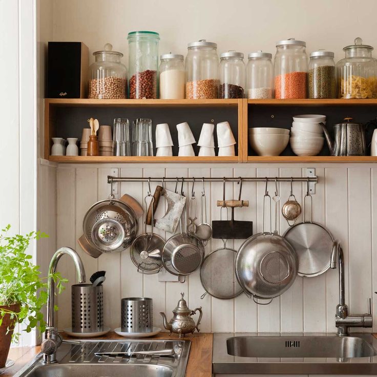 a kitchen with lots of pots and pans hanging on the wall above the sink