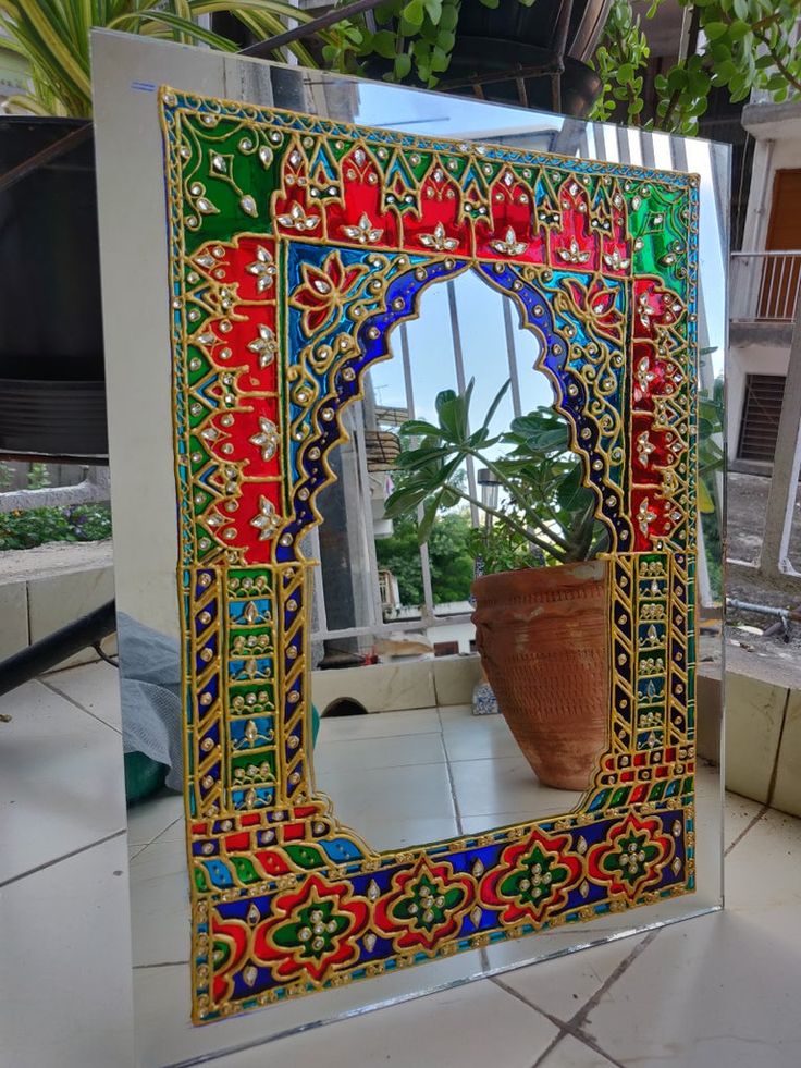 a decorative mirror sitting on top of a tiled floor next to a potted plant