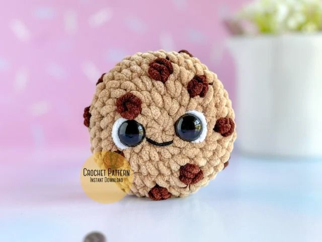 a crocheted stuffed animal with big eyes and brown spots on it's face