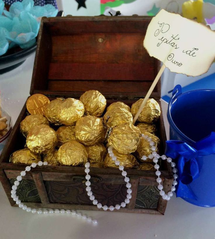 a wooden box filled with gold foiled chocolates on top of a white table