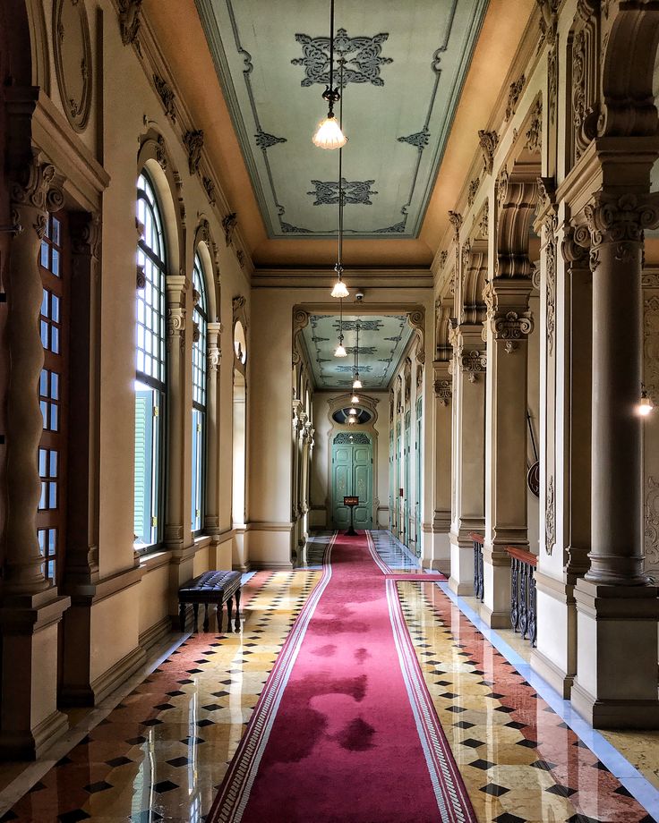 a long hallway with red carpet and windows