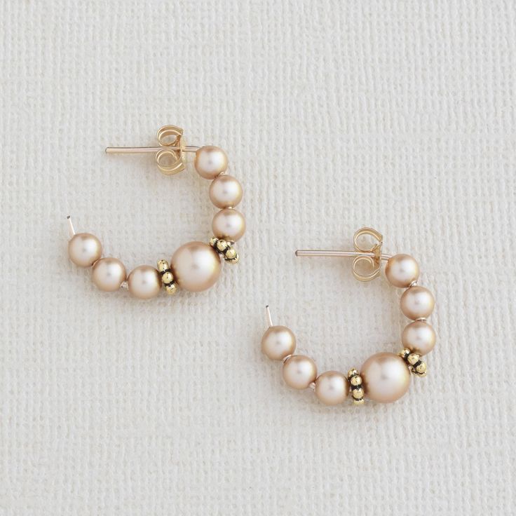 Our chic gold pearl hoop earrings are a timeless accessory that will elevate any outfit. The beaded earrings feature handmade 14k gold filled hoops adorned with luminous gold crystal pearls, carefully selected for their quality and beauty. The small hoop earrings are lightweight and perfect for everyday wear.  The push back closure ensures a secure and comfortable fit.  The classic design guarantees that they will never go out of style, making them an ideal Christmas gift for Mom. The pearls add a touch of sophistication and elegance to the hoops, creating a look that is both minimalist and refined.   Whether you're heading to work or out for a night on the town, these are a must-have addition to your jewelry collection - a long-lasting, beautiful, and versatile choice. EASY TO GIFT:  The Gold Pearl Huggie Earrings For Wedding, Everyday Gold Pearl Hoop Earrings, Everyday Gold Hoop Earrings With Pearls, Dainty Gold Pearl Hoop Earrings, Gold Pearl Hoop Earrings For Anniversary, Gold Hoop Earrings With Round Beads, Delicate Small Hoop Pearl Earrings In Gold, Gold 14k Gold-filled Hoop Earrings With Round Beads, Delicate Small Hoop Gold Pearl Earrings