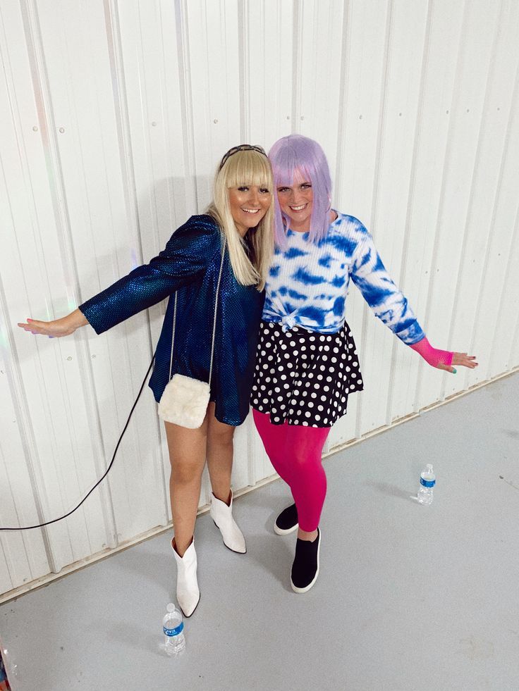 two women are posing for the camera in front of a white wall with blue and pink hair