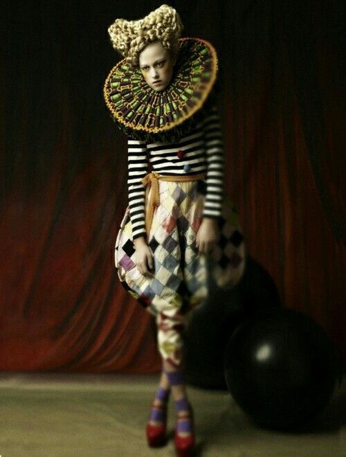 a woman in clown makeup standing next to a ball