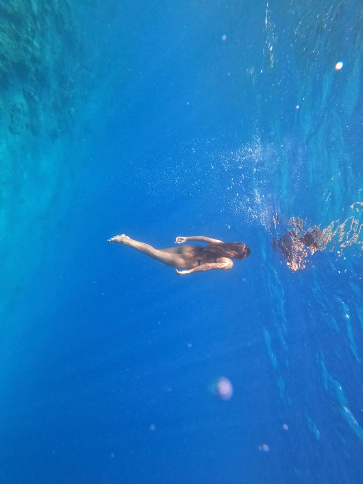 a man swimming in the ocean with his feet up on the water's surface