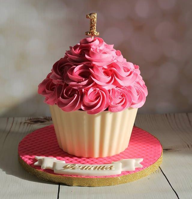 a cupcake decorated with pink icing on top of a plate