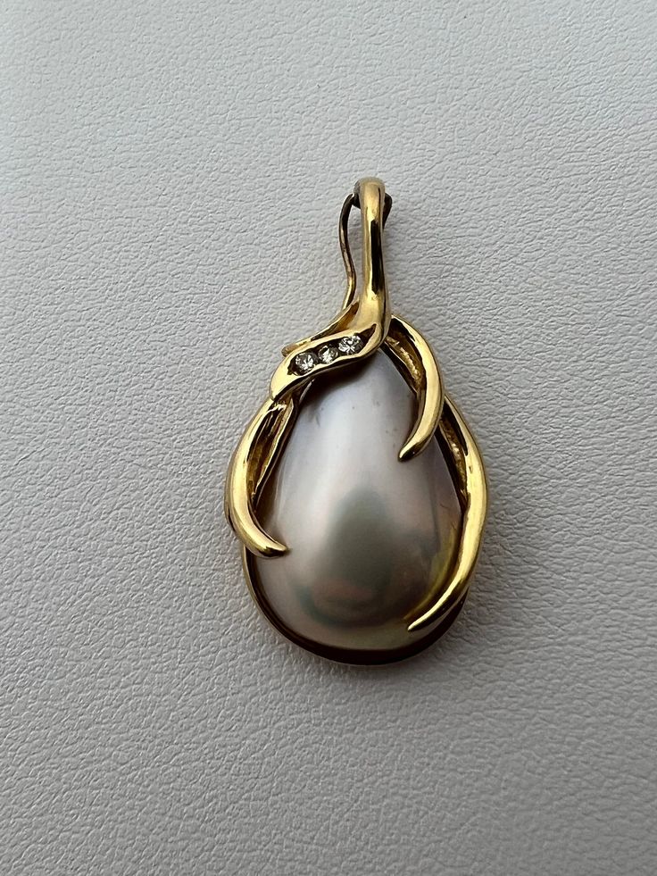 "A teardrop shaped Mother of Pearl encased by an elegant frame of 14K gold (stamped \"14K\") with three small diamonds embedded in it. This item weighs 4.6 grams with a length of 1.2 inches and the bail fits a 5mm chain, also works as a hinge to complement any pearl strand." Elegant Gold Teardrop Pendant Jewelry, Exquisite Teardrop Jewelry For Formal Occasions, Exquisite Formal Jewelry With Teardrop Pendant, Exquisite Teardrop Pendant Jewelry For Formal Occasions, Gold Teardrop Jewelry For Formal Occasions, Gold Teardrop Jewelry For Formal Events, Formal Teardrop Jewelry With Polished Finish, Gold Teardrop Pendant Jewelry For Formal Occasions, Teardrop Yellow Gold Jewelry With High Luster