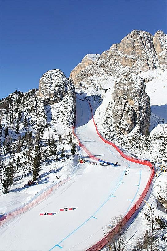 a snow covered ski slope with mountains in the background