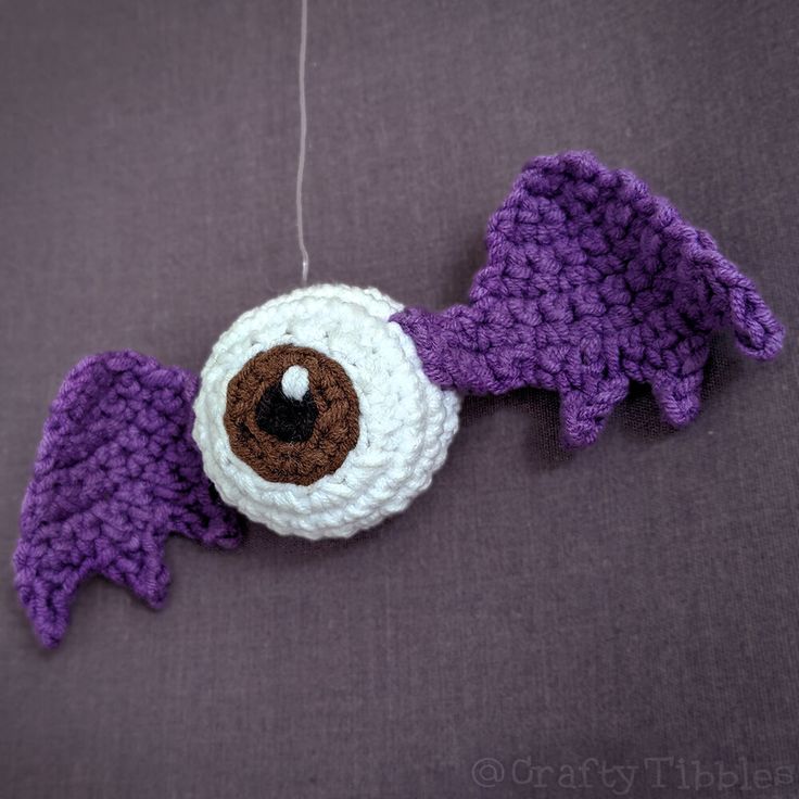 a crocheted purple and white object with two wings hanging from it's side