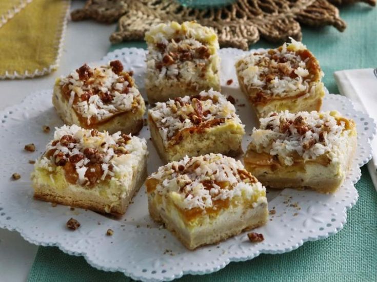 several pieces of dessert sitting on a white doily next to a fork and napkin