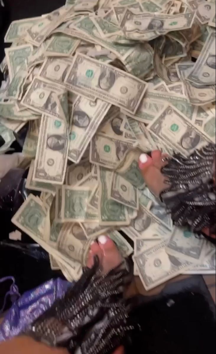 a pile of money being held by someone's hands with gloves on top of it