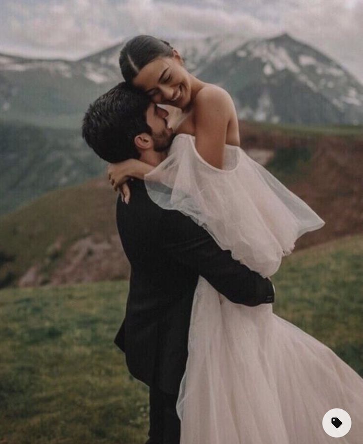 a bride and groom embracing in the mountains