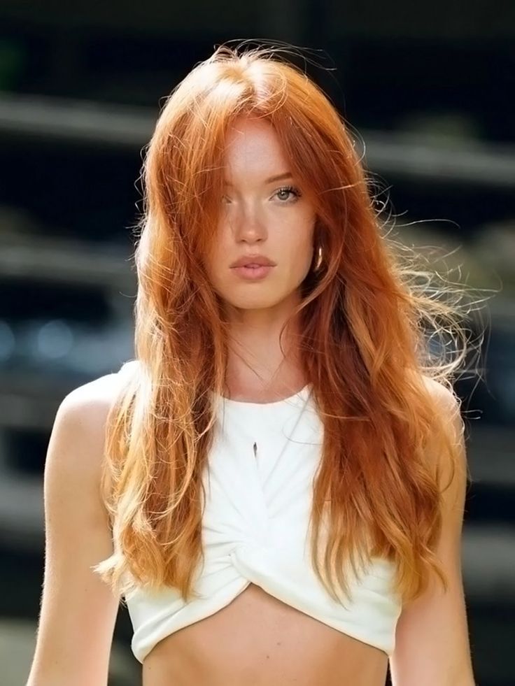 a woman with long red hair wearing a white top