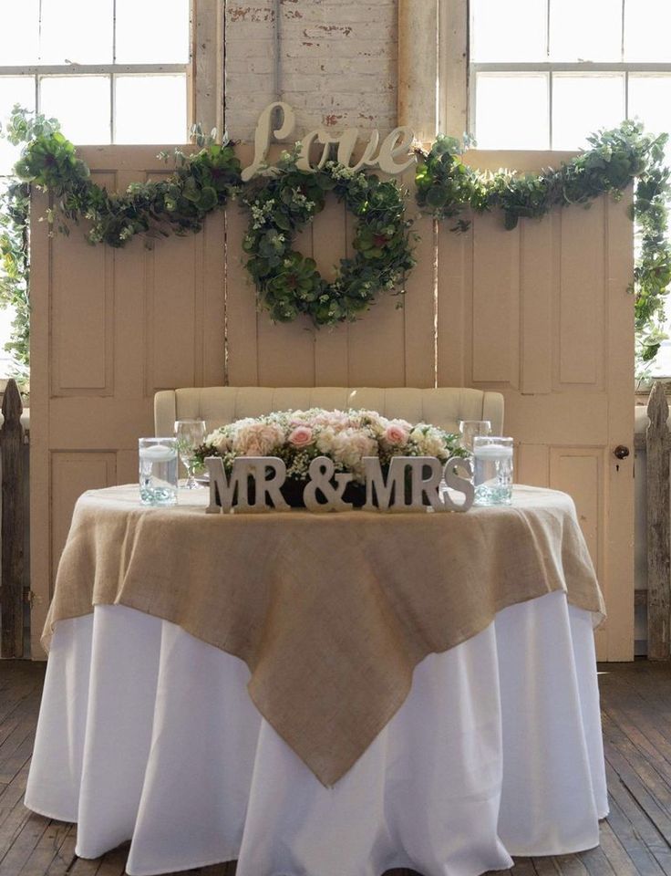 a table with flowers and greenery on it in front of a sign that says mr & mrs