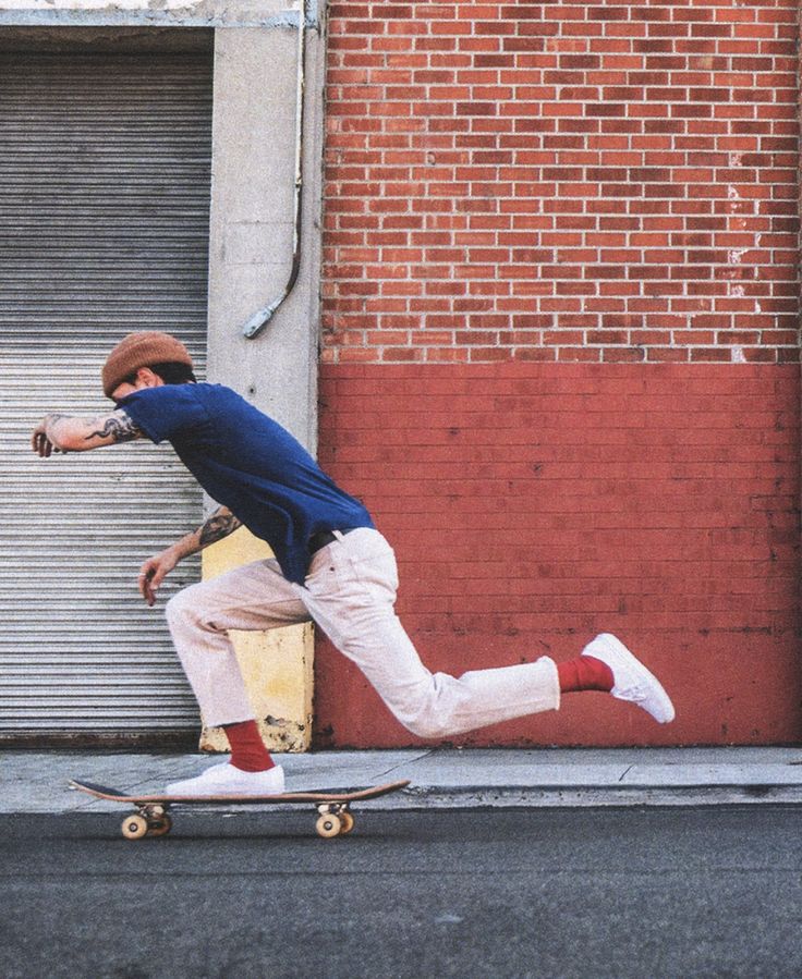 a man riding a skateboard down the side of a road next to a building