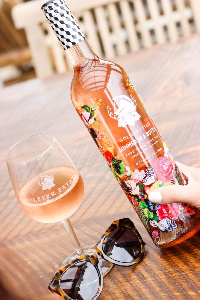 a person holding a bottle and glasses on a table