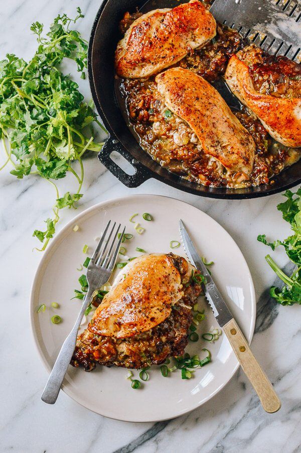 two pieces of chicken in a skillet on a plate with a knife and fork