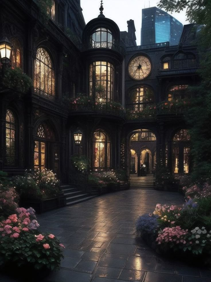 a large building with many windows and lots of flowers in the front yard at night