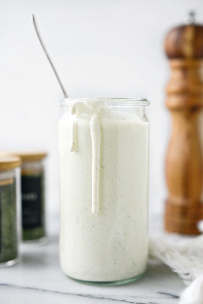 a jar filled with white liquid sitting on top of a table next to some spices