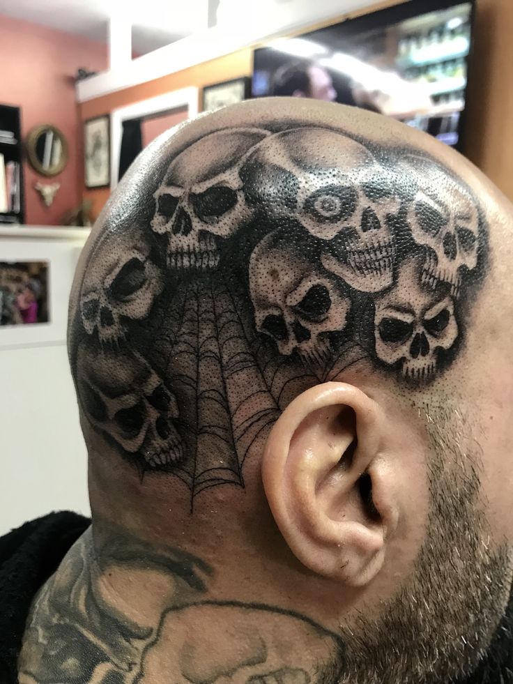 a man with tattoos on his head and skulls behind him