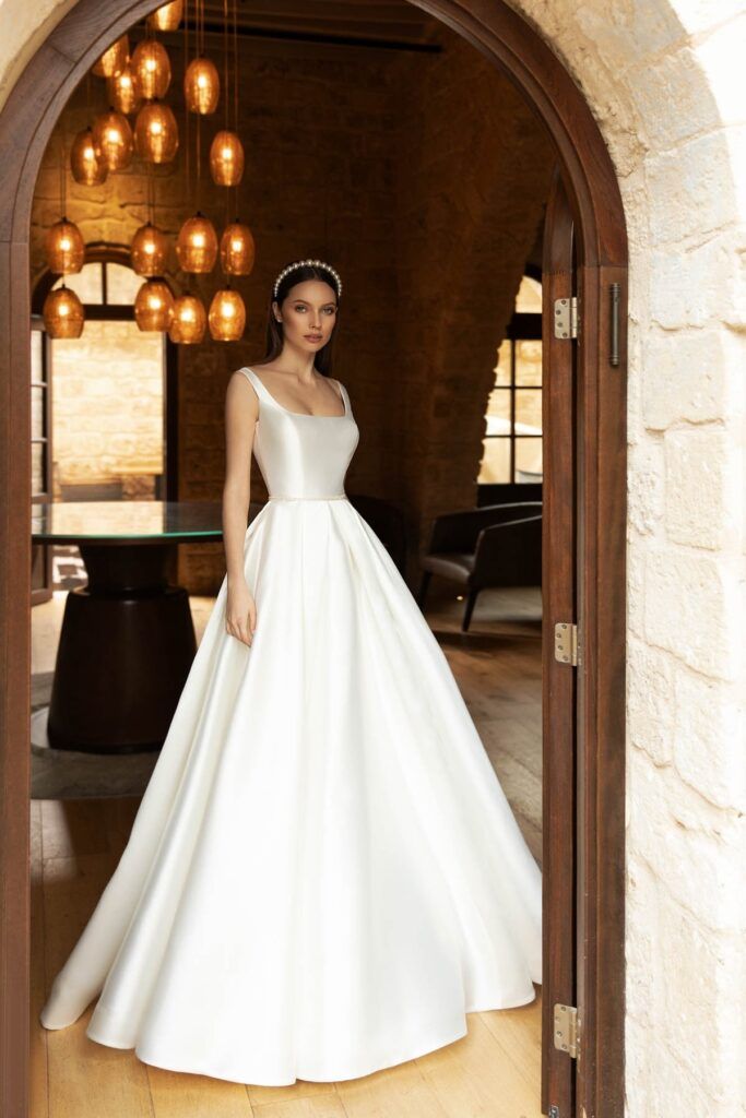 a woman in a white wedding dress standing by an open doorway with lights hanging from the ceiling