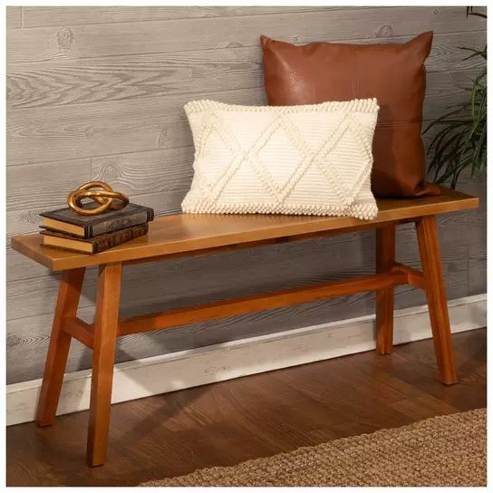 a wooden bench with a pillow and some books on it