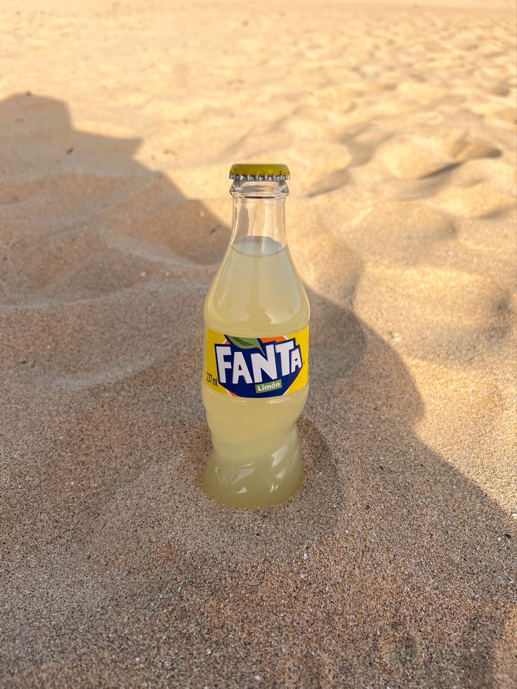 a bottle of fanta is sitting in the sand