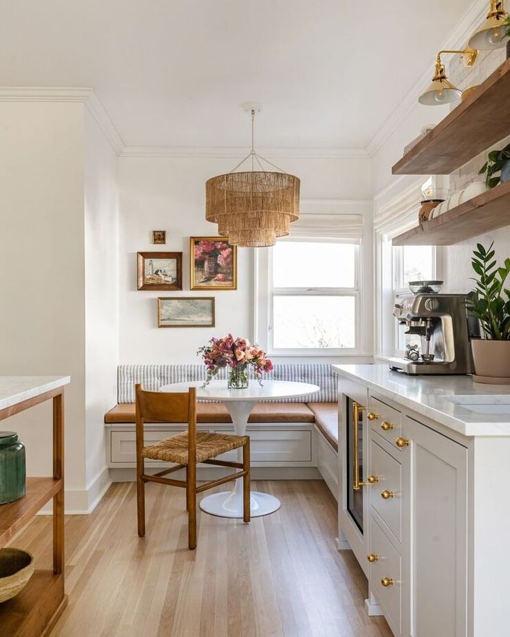 a kitchen with wooden floors and white walls, along with a breakfast nook that has built - in shelving on the wall