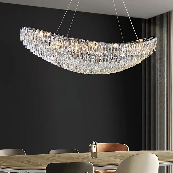 a chandelier hanging over a dining table in a room with black walls and chairs