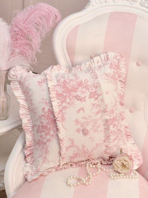 pink and white striped chair with decorative pillows on the armrests next to a vase filled with flowers