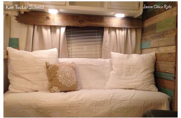 a white bed sitting in the corner of a room next to a cabinet and window