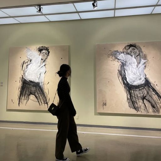 a woman walking past two paintings in an art gallery