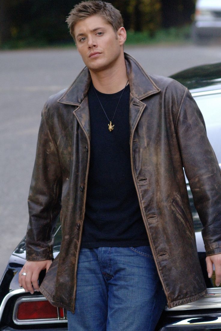 a man standing next to a car wearing a brown leather jacket